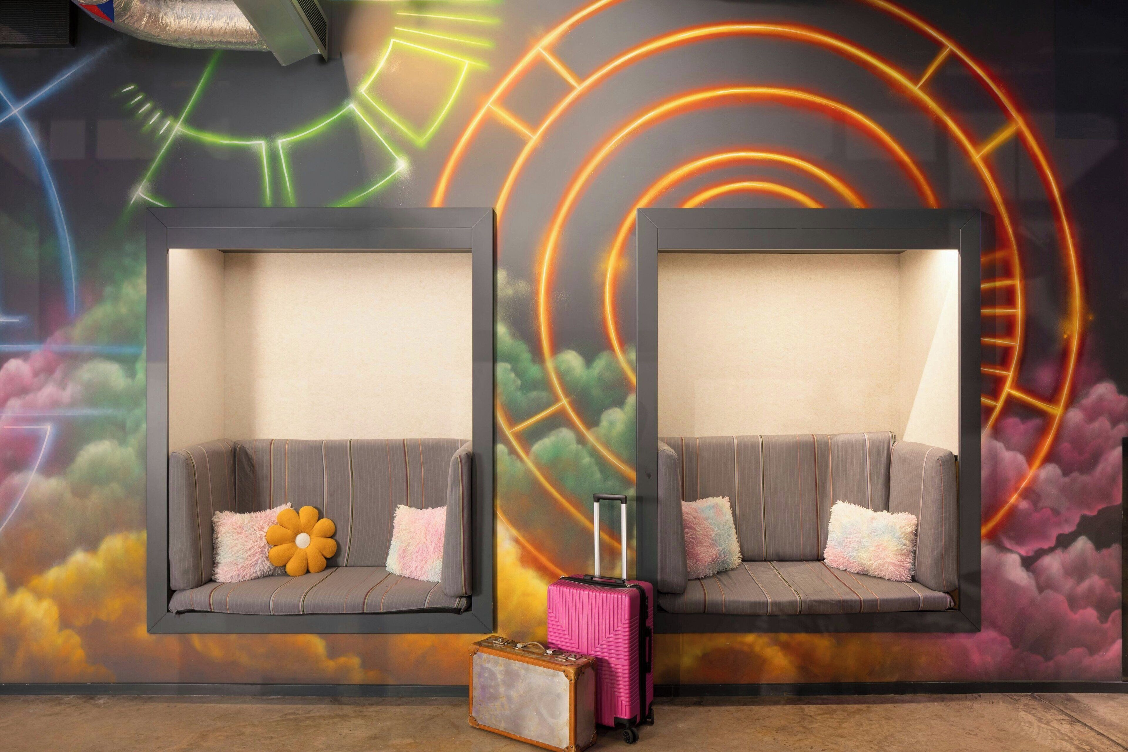 Two cushioned seating areas with a suitcase and a vintage suitcase on the floor.