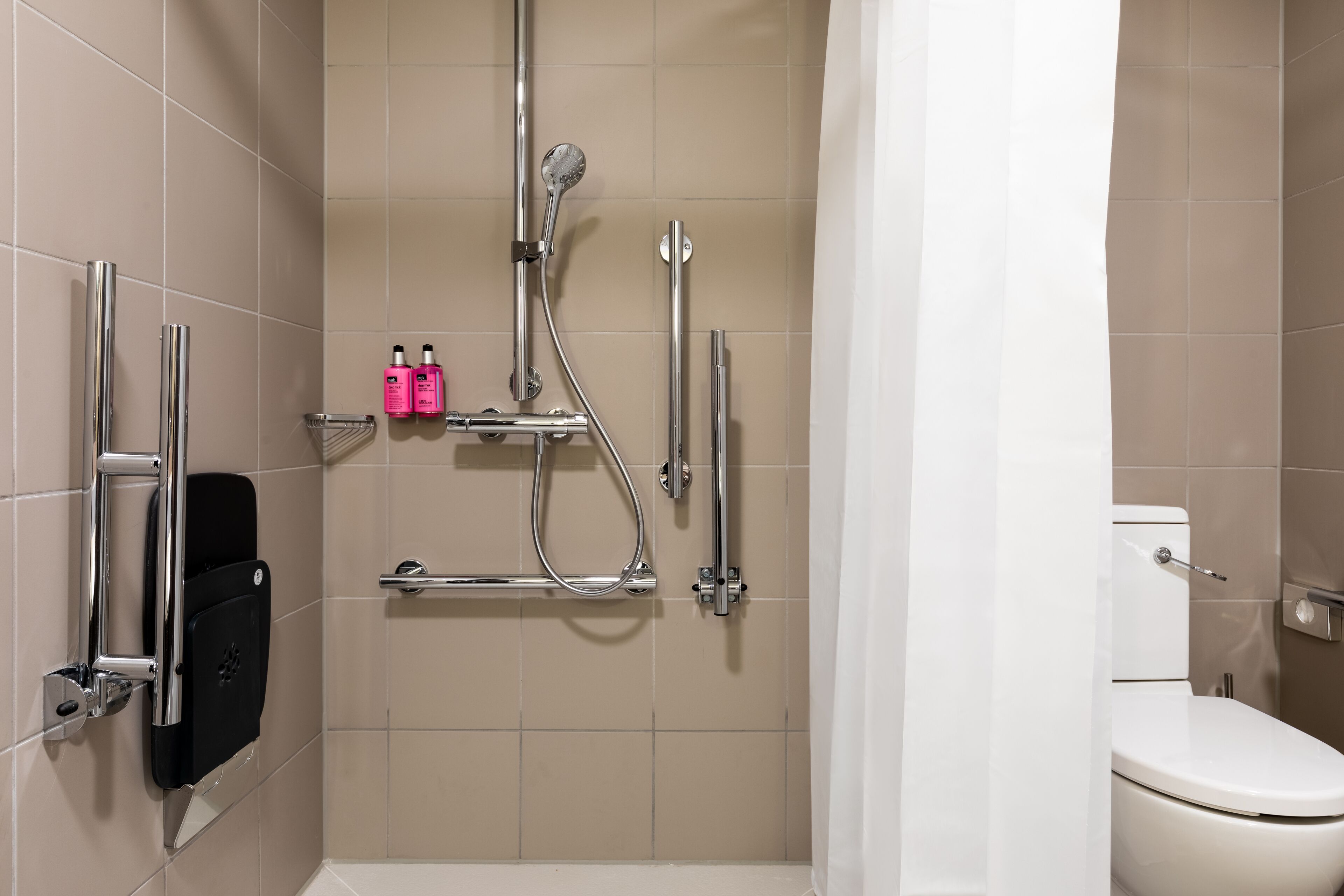 Un baño moderno con ducha, inodoro y secador de manos.