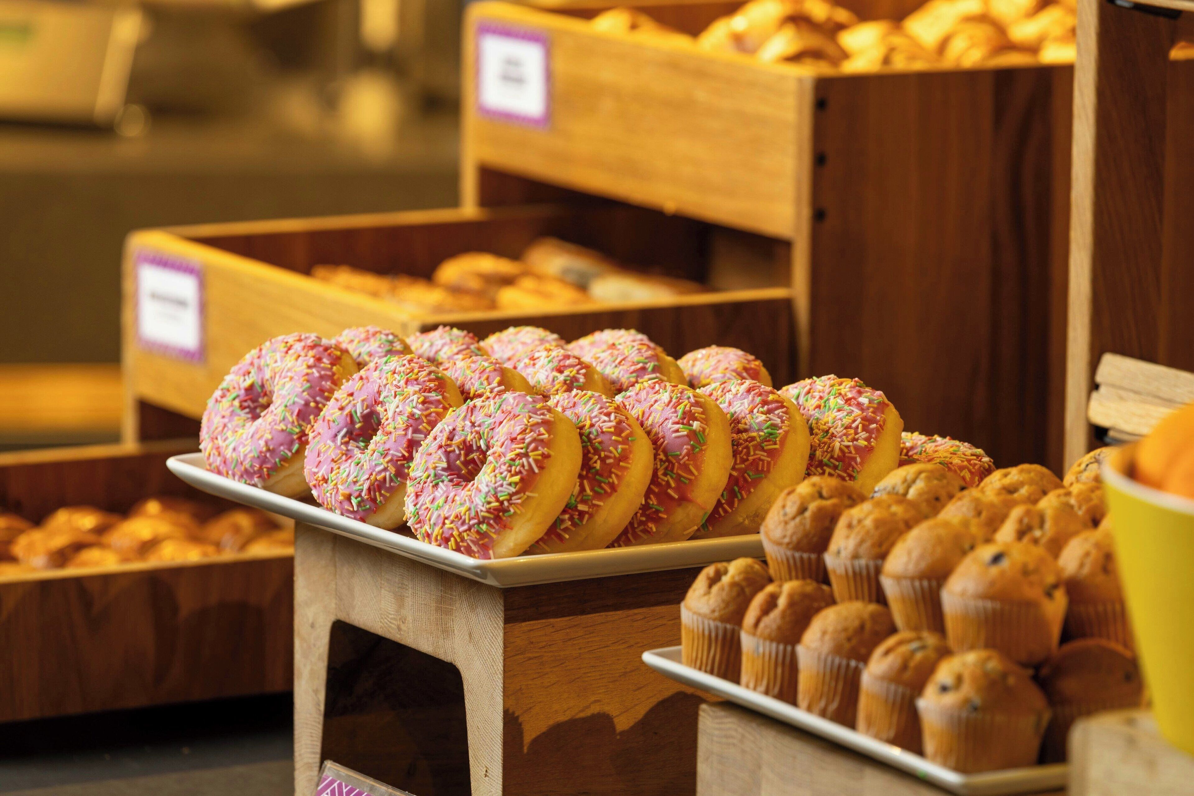 A bakery display with various baked goods including donuts and muffins.