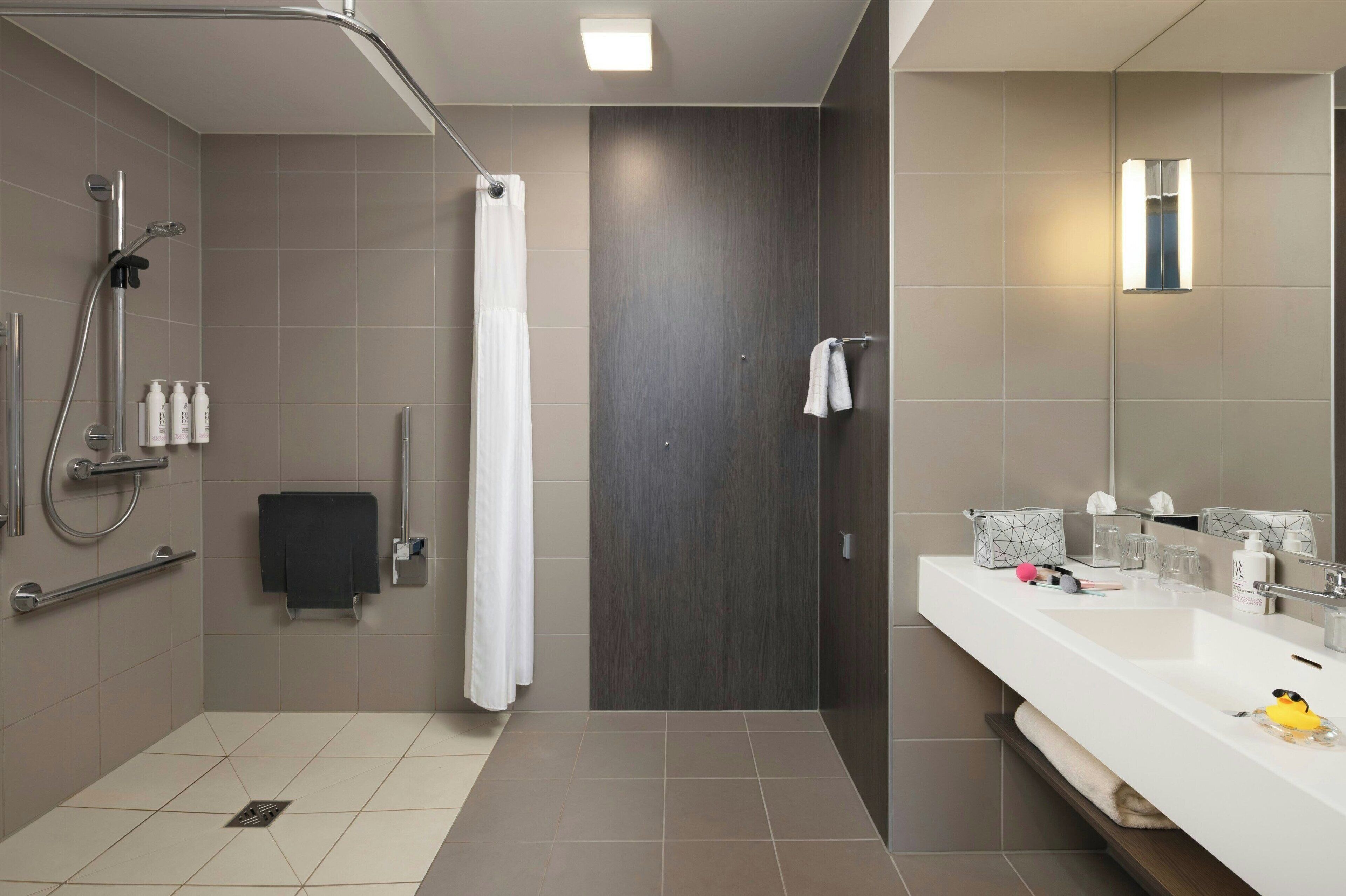 A modern bathroom with a shower, toilet, and sink.
