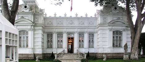 A grand building with a symmetrical facade, large windows, and a central entrance with a staircase.