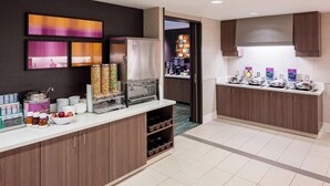 Une cuisine d’hôtel moderne équipée d’un coin café, d’un réfrigérateur et d’un comptoir pour le petit-déjeuner.