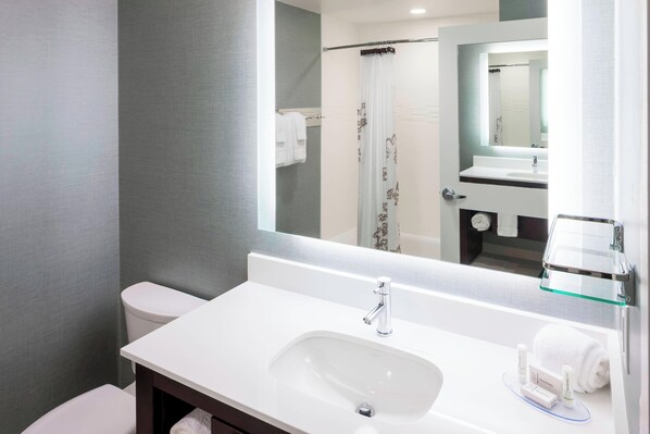 A modern bathroom with a white sink, mirror, and toilet.