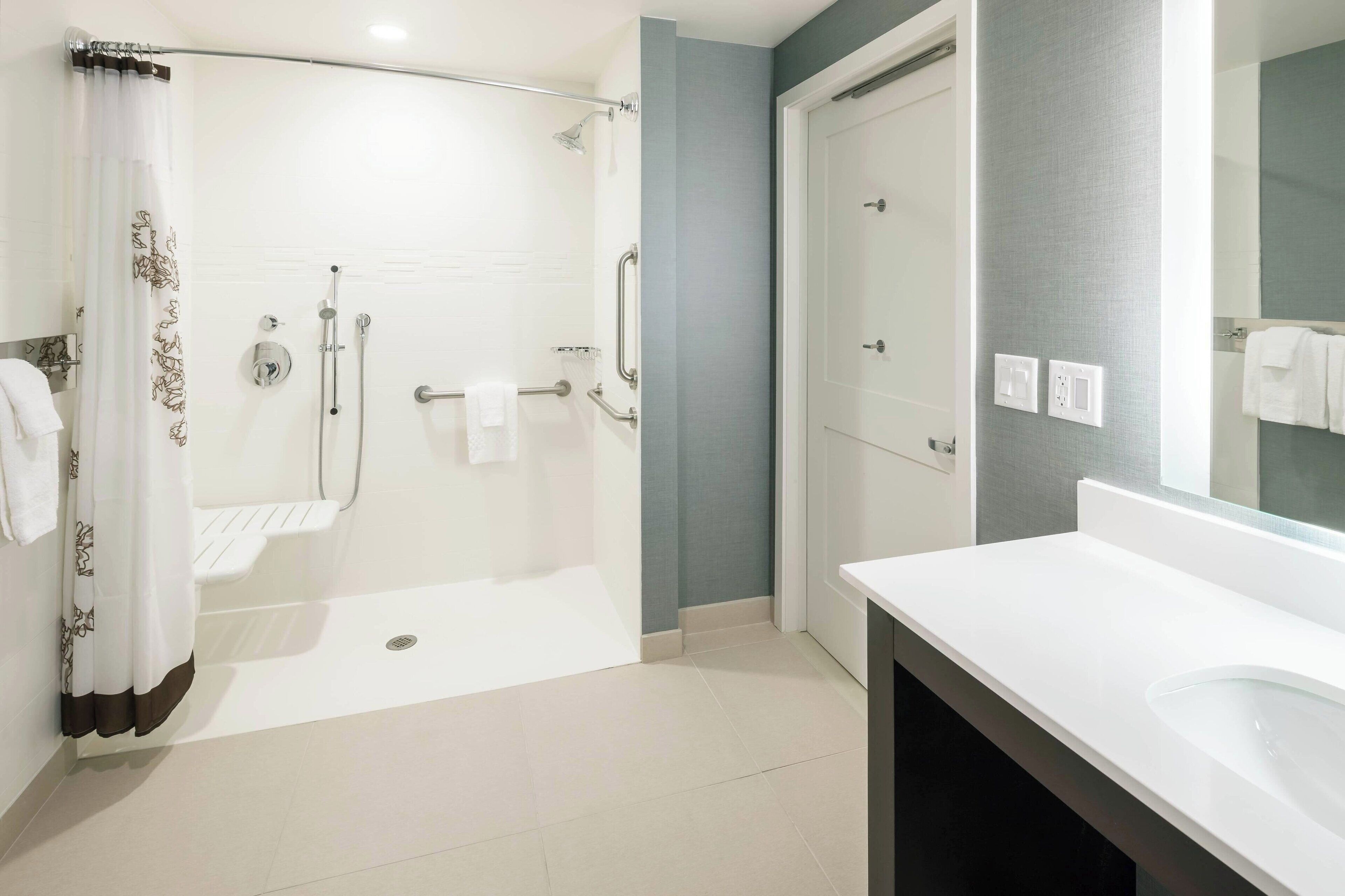 Une salle de bain moderne équipée d’une douche, d’un lavabo et d’un miroir.