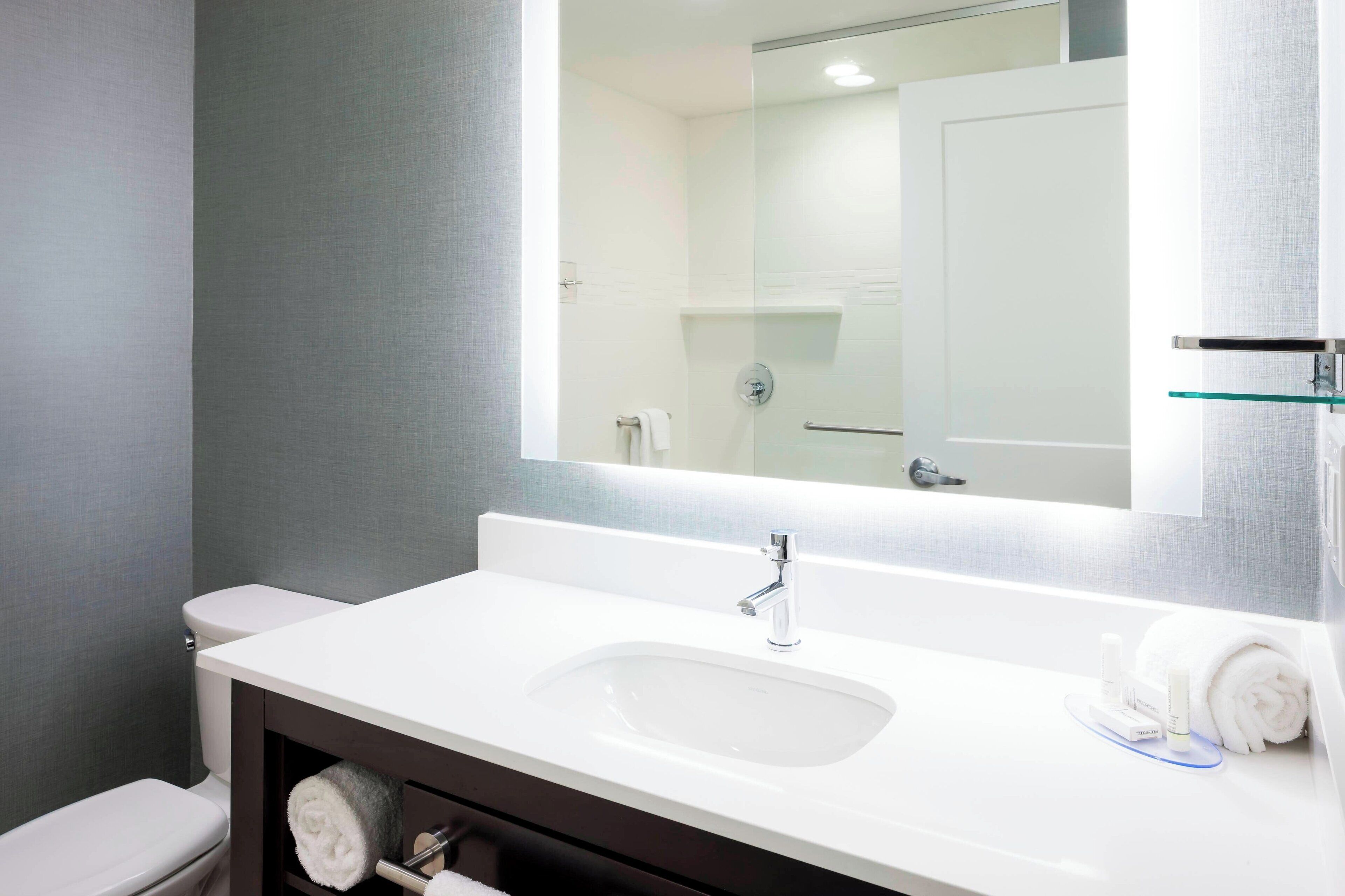 A modern bathroom with a white sink, a mirror, and a toilet.