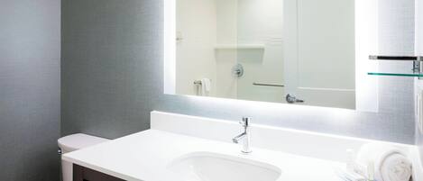 Une salle de bain moderne avec un lavabo blanc, un miroir et des toilettes.
