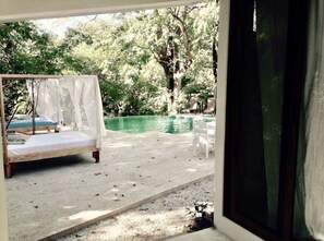 A bedroom with a bed, a small pool, and outdoor seating.