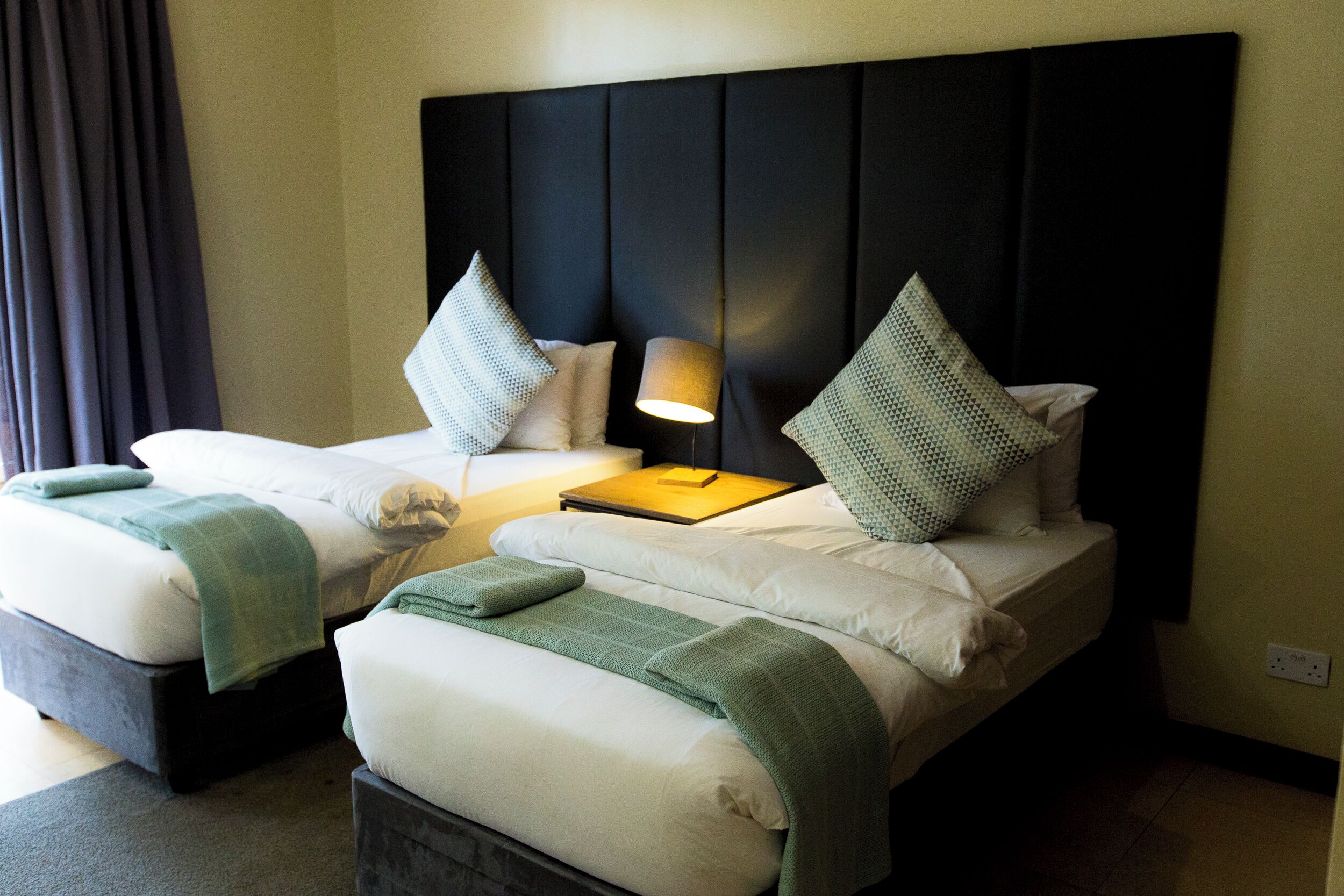 Une chambre d’hôtel avec deux lits, une tête de lit et une lampe.
