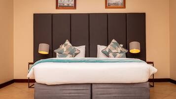 A double bed with a dark headboard, two bedside lamps, and decorative pillows.
