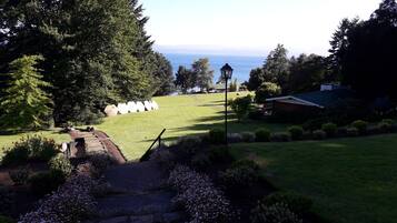 Un jardín con un sendero de piedra, césped y vista al mar.