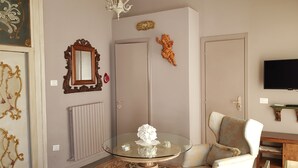 A living room with a glass coffee table, a white sofa, a television, and decorative items on the walls.