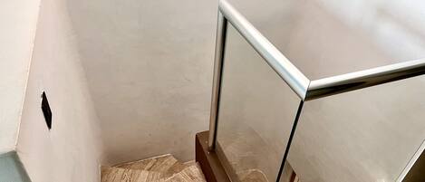 A staircase with a glass railing and a wooden floor.