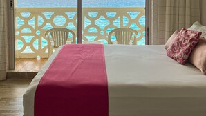 A hotel room with a bed, a view of the sea, and a balcony with a railing. - Ocean View Apartments (Cancun)
