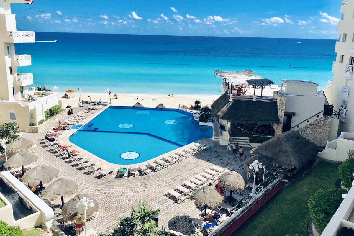 Un resort con una amplia piscina, acceso a la playa y vistas al océano.