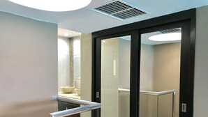 A modern bathroom with a glass door, a beige countertop, and a visible sink. - Ocean View Apartments – Increíble (Cancun)