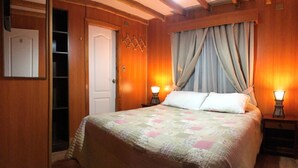 Un dormitorio con cama, dos lámparas de noche, una puerta de madera y un espejo.
