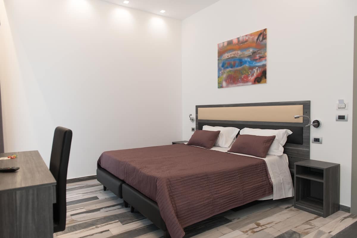 A modern bedroom with a bed, bedside tables, a desk, and a chair.