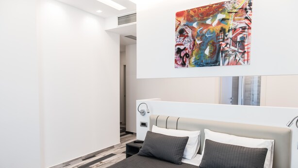 Una moderna camera d'albergo con un ampio letto, un comodino e un'opera d'arte appesa al muro.