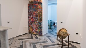 Un corridoio con un murale astratto dai colori vivaci, un globo su un supporto e un pavimento con motivo a spina di pesce.