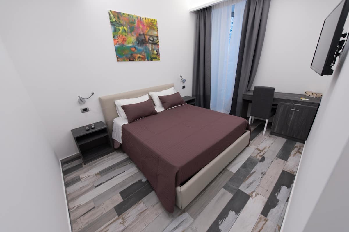 A modern hotel room with a large bed, a desk, and a chair.