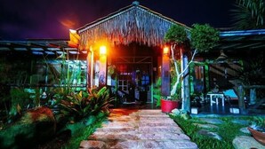 A building with a thatched roof and a stone pathway leading to the entrance. - Pousada Rosa da Praia (Imbituba)