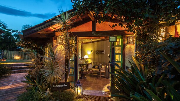 A cozy, well-lit entrance with a reception desk, seating area, and a sign reading "Recepção". - Pousada Rosa da Praia (Imbituba)