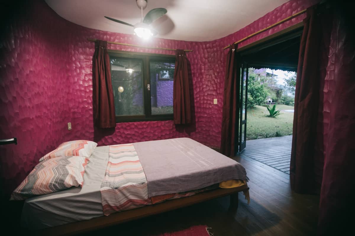 A bedroom with a bed, a window, and a view of the outdoors.