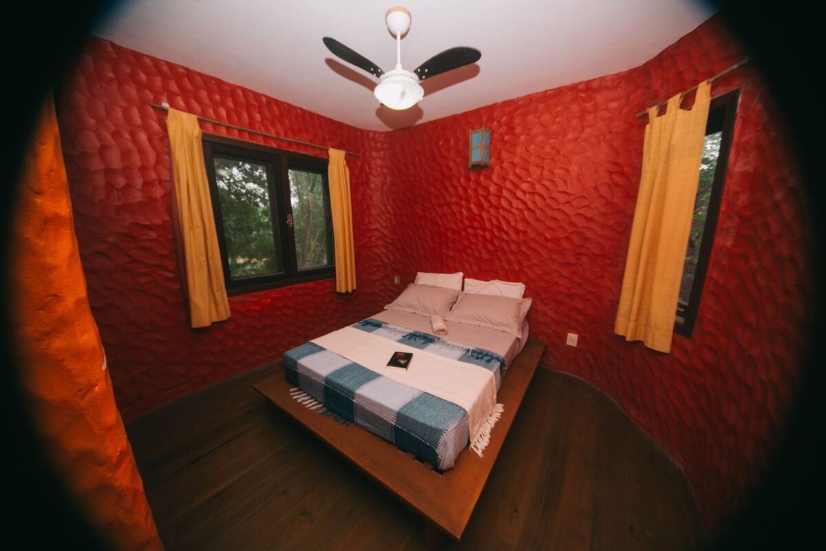 A bedroom with a bed, a ceiling fan, and a window with curtains.