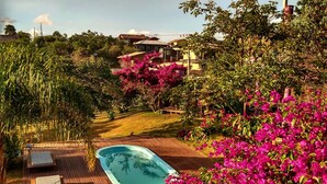 Ein Schwimmbecken, umgeben von üppigem Grün und leuchtend rosa Blüten.