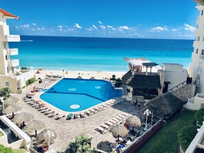 A resort with a large swimming pool, beach access, and a view of the ocean. - Ocean View Apartments – Delicia (Cancun)