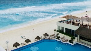 A beachside hotel with a pool, beach umbrellas, and a view of the ocean. - Ocean View Apartments – Delicia (Cancun)