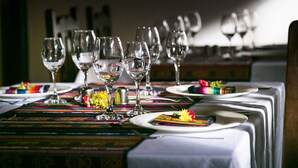 Une table à manger dressée avec de nombreux verres à vin, des assiettes et un chemin de table aux couleurs vives.