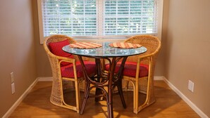 A corner room with a glass table and wicker chairs, a window with blinds, and wooden flooring. - Spacious Country Guest Apartment (Eugene)