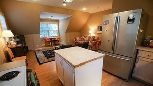 A compact kitchen with a refrigerator, stove, and a small dining area with a chair and table. - Spacious Country Guest Apartment (Eugene)