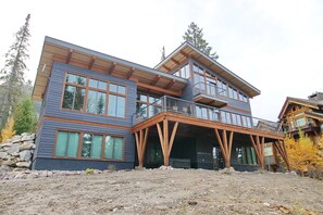 Ein modernes Haus mit zwei Etagen, großen Fenstern, einem Balkon und einem Steinfundament.