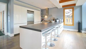 Une cuisine moderne dotée d’un grand îlot central, de tabourets de bar et offrant une vue sur l’extérieur grâce à une fenêtre.