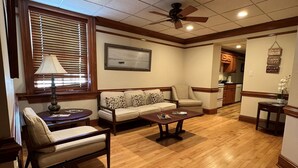 A spacious living room with a wooden floor, a sofa, a coffee table, and a ceiling fan. - Historic Downtown Condo-1 Bedroom (New Bern)