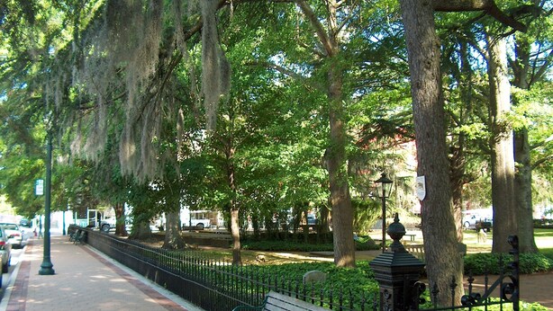 A park with a paved walkway, benches, a fire hydrant, and a fence. - Historic Downtown Condo-1 Bedroom (New Bern)