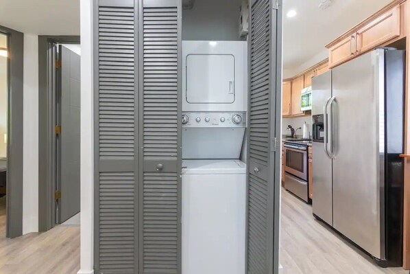 A compact kitchen with a built-in washer and dryer, a stainless steel refrigerator, and wooden cabinets. - Private Charming Guesthouse in Little Havana, perfect place for the World Cup (Miami)