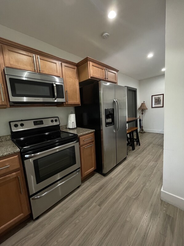 A modern kitchen with stainless steel appliances, wooden cabinets, and a granite countertop.