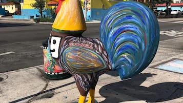 A colorful rooster sculpture on a sidewalk.