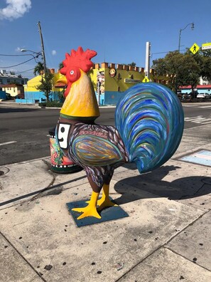 Una escultura colorida de gallo en una acera.