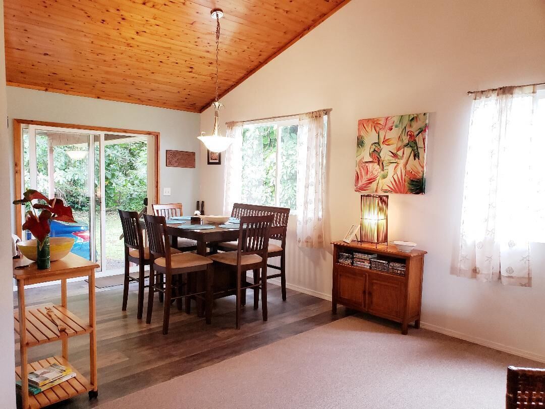A dining area with a wooden table and chairs, a wooden cabinet, and a painting on the wall.