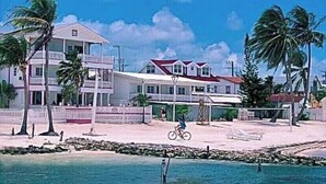 A beachfront property with a two-story building, a sandy beach, and a clear blue sky.