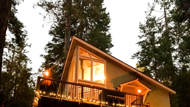 Une cabane avec une terrasse, un foyer extérieur et des fauteuils Adirondack rouges.
