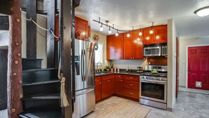 Une cuisine moderne avec des meubles en bois, des appareils électroménagers en acier inoxydable et un four encastré.