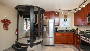 Une cuisine dotée d’un îlot central, d’appareils électroménagers en acier inoxydable, de meubles de rangement en bois et d’une cuisinière intégrée.