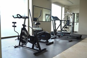 A gym with stationary bikes, a treadmill, and weight machines. - Hg Hotel (Zapopan)