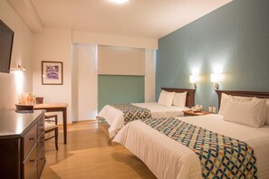 A hotel room with two beds, a desk, a chair, and a television. - Hg Hotel (Zapopan)