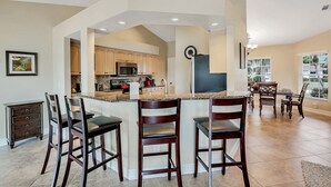 A spacious kitchen with a large island, wooden chairs, and a dining area with a table and chairs. - RARE Waterfront Western Exposure Vacation Home - Best Sunset Views & FREE WiFi (Marco Island)